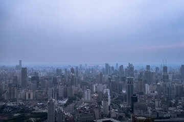 Aerial view of Shanghai city skyline under cloudy evening sky, showing dense high-rise buildings and sprawling urban layout.