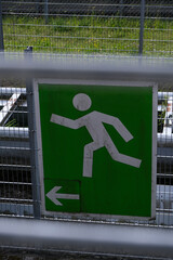 A green sign with a man running on it and an arrow pointing to the left