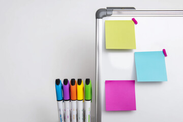 Colorful markers and sticky notes on a whiteboard at a workspace