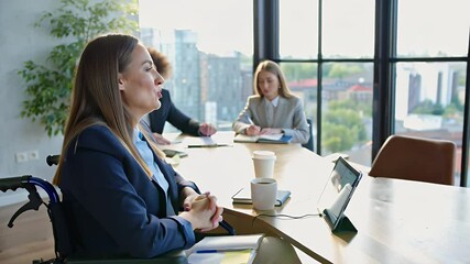 Confident businesswoman in wheelchair leading executive meeting in bright modern office with city view through large windows, coworkers listening and taking notes out of focus in the background - Powered by Adobe