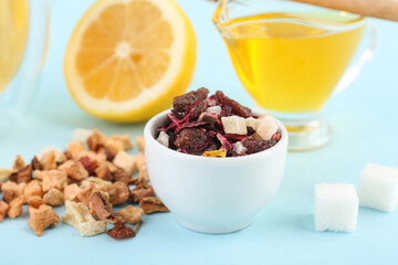 Bowl with dried fruit tea, sugar and honey on blue background, closeup