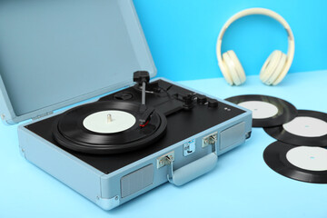 Record player with vinyl disks and headphones on blue table
