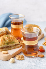 Wooden board with glasses of tea and Turkish delight on light background