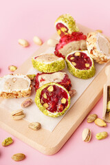 Wooden board with tasty Turkish delight on pink background