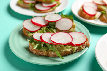 Plates with delicious radish bruschettas on turquoise background