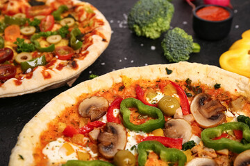 Vegetables pizzas with ingredients on dark background