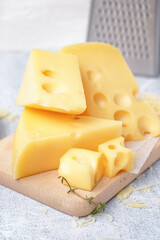 Board with pieces of Swiss cheese on white table