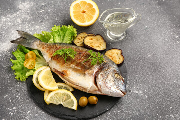 Slate board with tasty grilled dorado fish on grunge background