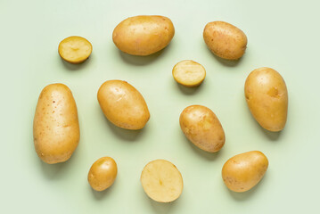 Raw potatoes on green background