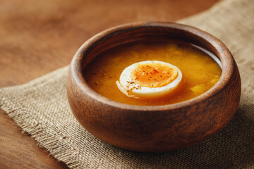 Creamy pumpkin soup with boiled egg served in rustic wooden bowl, evoking warmth and comfort