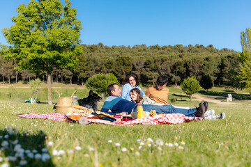 Family having fun, eating and playing with their dog during a picnic in a park