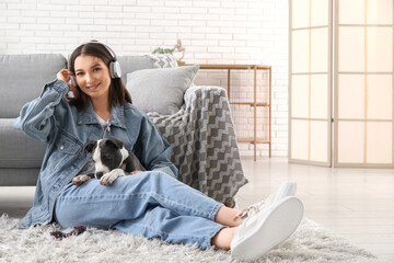 Beautiful young woman in headphones with pet toy and cute staffordshire terrier puppy at home