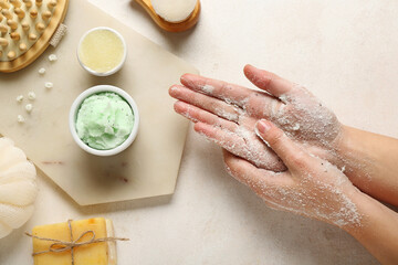 Woman applying scrub onto hands on light background, closeup