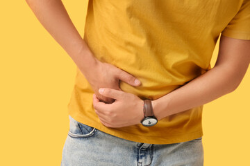 Young man with appendicitis on yellow background, closeup
