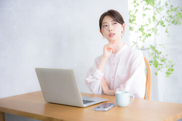 パソコンの前で考える　オフィスカジュアルのイメージ　シアーシャツの女性転職どうしようかな？見上げる, 