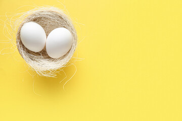 Nest with raw chicken eggs on yellow background