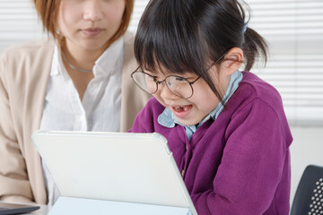 タブレットを使って眼鏡をかけた女の子は楽しそうに勉強する