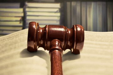 Closeup of judge gavel and open book in library background