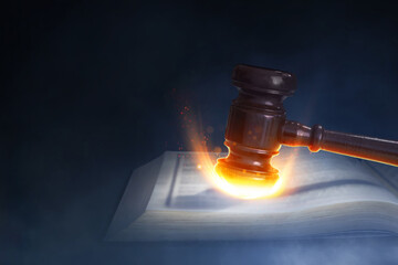 Hammer hitting book page with fire burning effect on dark smoke background