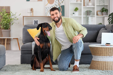 Young man hugging Dobermann dog at home