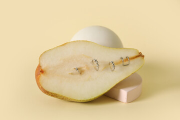 Half of pear with piercing on light yellow background
