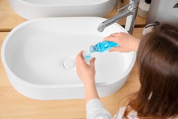 Woman with bottle of mouth rinse in bathroom