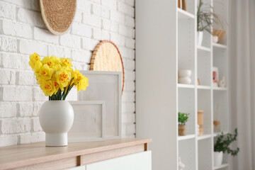 Vase with narcissus and blank frames on shelf in living room, closeup