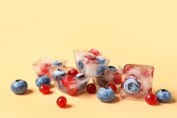 Frozen blueberries and cranberries in ice cubes on orange background