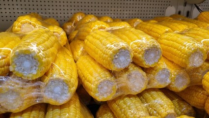 Plastic packaging of fresh sweet corn (Zea mays) kept for sale in a Supermarket. Yellow sweetcorn on shelf an organic store in shopping mall. Product display in grocery store produce section. Optimizi
