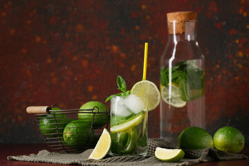 Glass and bottle of fresh Mojito cocktail with mint on red background