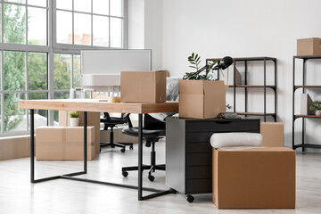 Workplace and chest of drawers with cardboard boxes in office on moving day