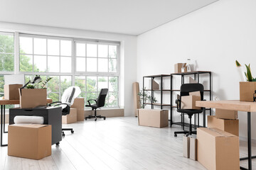Interior of office with workplace, shelf units and cardboard boxes on moving day