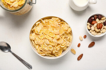 Composition with bowls of tasty cornflakes and nuts on white background, closeup