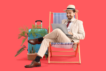 Businessman using laptop in deck chair with palm tree and suitcase on red background. Summer vacation concept