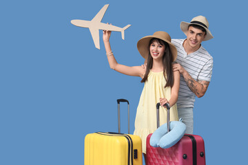 Couple of tourists with paper airplane and suitcases on blue background
