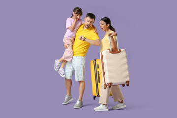 Fototapeta premium Shocked family of tourists with suitcases looking at wristwatch on lilac background