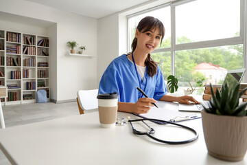 Female medical intern studying with laptop at table in library
