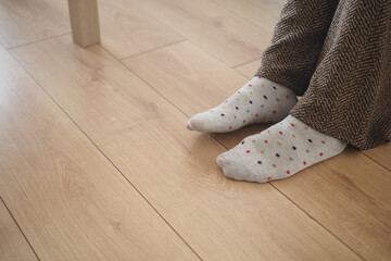 Cozy feet in patterned socks on wooden floor