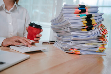 An office worker in a white shirt organizes a large stack of documents with colorful paper clips and folders.