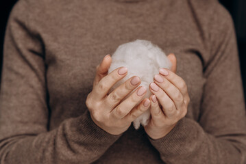 Cotton or wool ball in female hands.