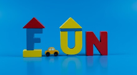 Colorful wooden letters spelling FUN with small toy car and houses