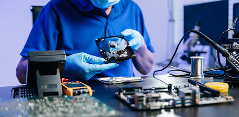 Hard disk drive on the technician's desk and a computer motherboard as a component. the concept of...
