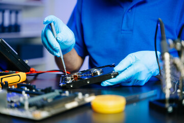 Hard disk drive on the technician's desk and a computer motherboard as a component. the concept of...