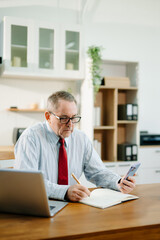 Mature Businessman using laptop while sitting at home. man sitting in kitchen and doing market research working