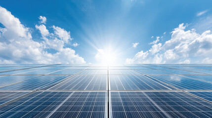 Solar panels array tilting toward sun under blue sky with clouds and bright sunlight shining, symbolizing clean energy and sustainability
