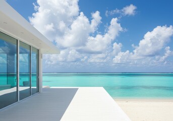 Fototapeta premium A modern white house with large glass windows overlooks a pristine turquoise ocean and sandy beach