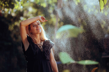 Woman Relaxes with a Cooling Water Sprinkler. Person finds comfort in a mist of water on a hot summer day 
