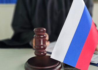 Russian flag displayed next to a gavel in a courtroom during a legal proceeding