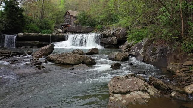 Experience the vibrant colors of spring at Babcock State Park, showcasing the historic grist mill beside a tranquil creek and enchanting waterfall.