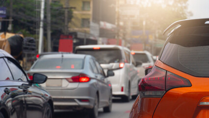 Fototapeta premium Luxury of orange car driving on the asphalt road. Traveling in the provinces during the bright period. Many cars are driving on a congested road in the city.